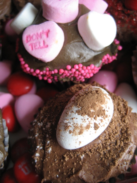 Jordan almond dusted with cocoa powder, conversation hearts arranged on dark chocolate frosting rimmed with pink non-pareils